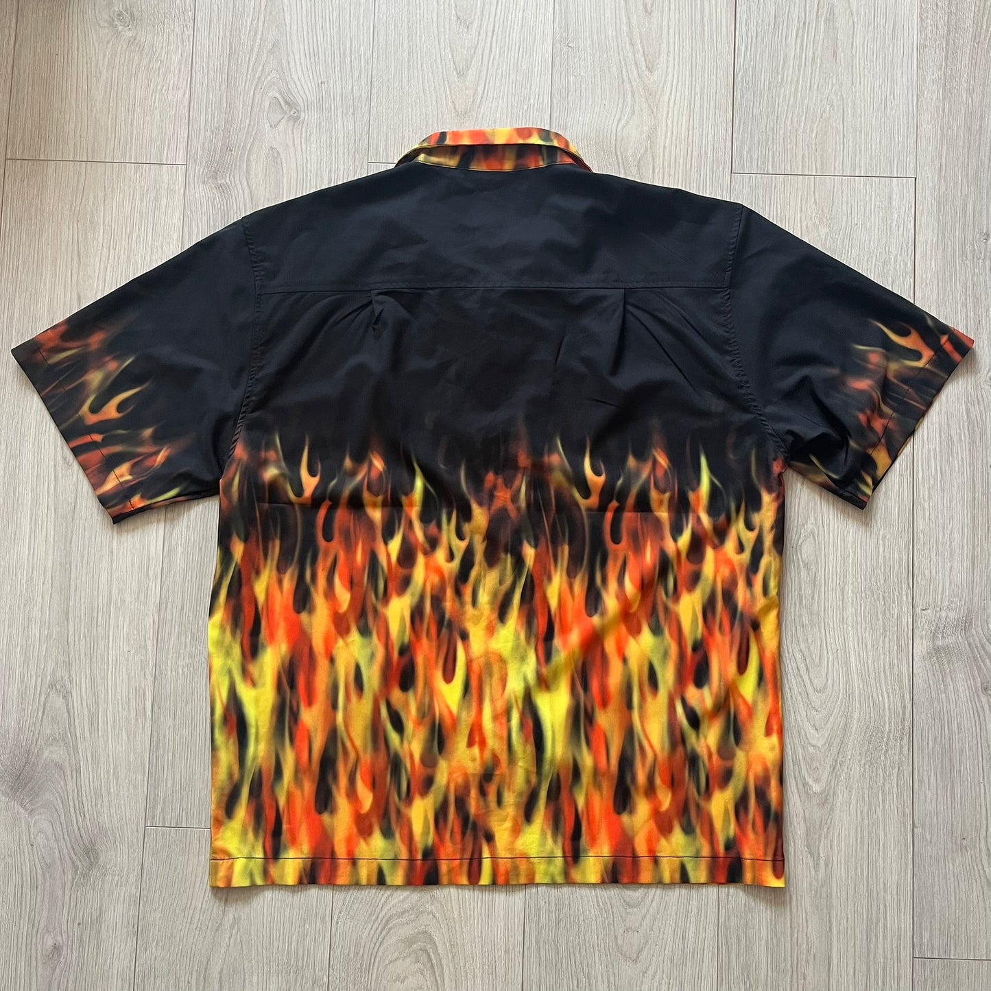 Black shirt with flame pattern on a wooden floor