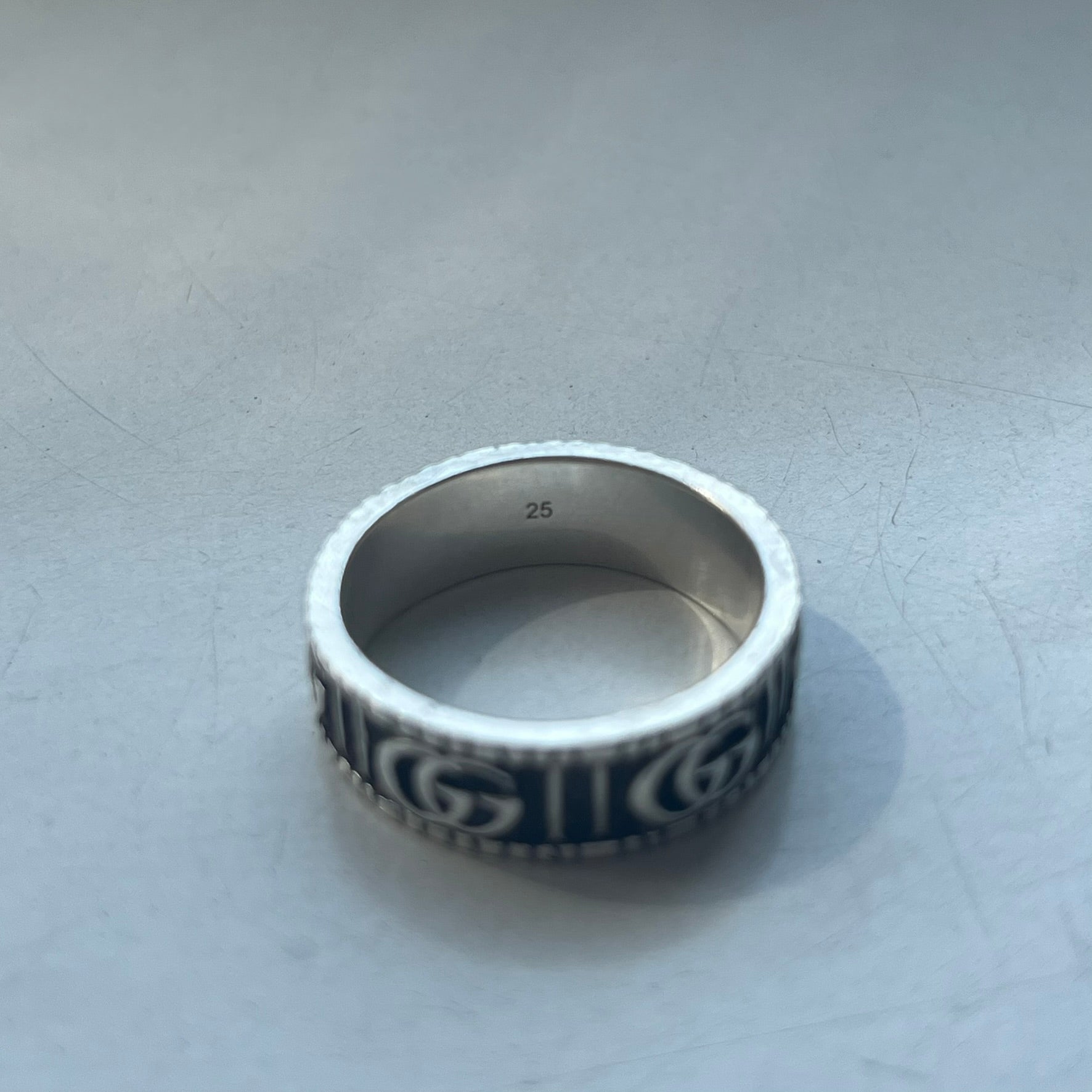 Silver ring with intricate design on a light gray background