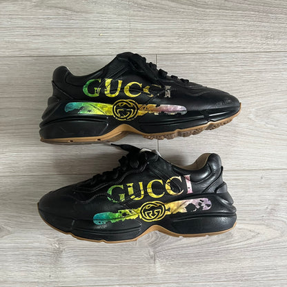 Black Gucci sneakers with colorful design on a wooden floor