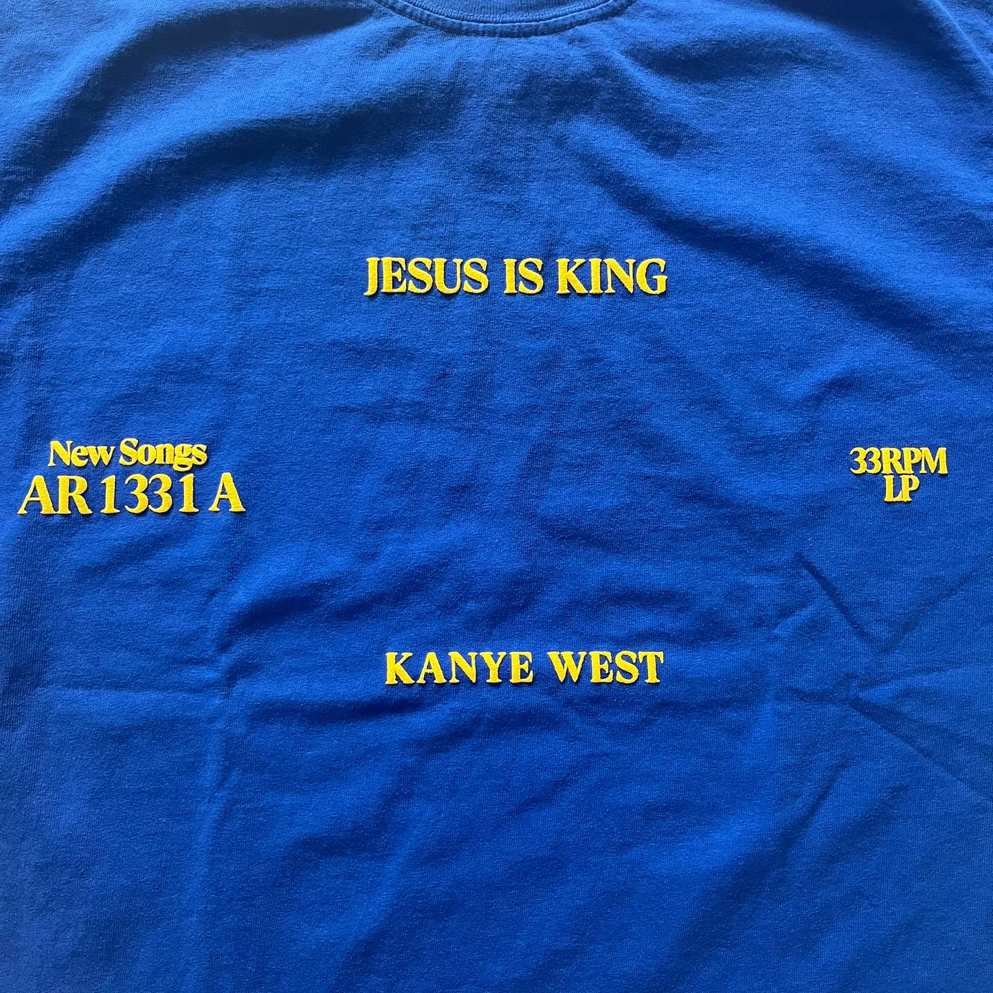 Blue t-shirt with yellow text about Kanye West's album 'Jesus Is King'.
