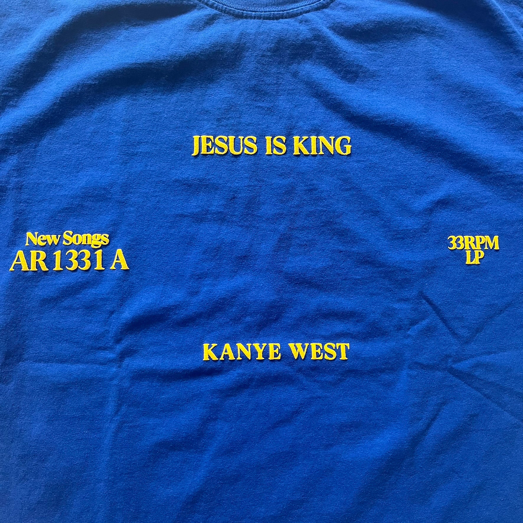 Blue t-shirt with yellow text about Kanye West's album 'Jesus Is King'.