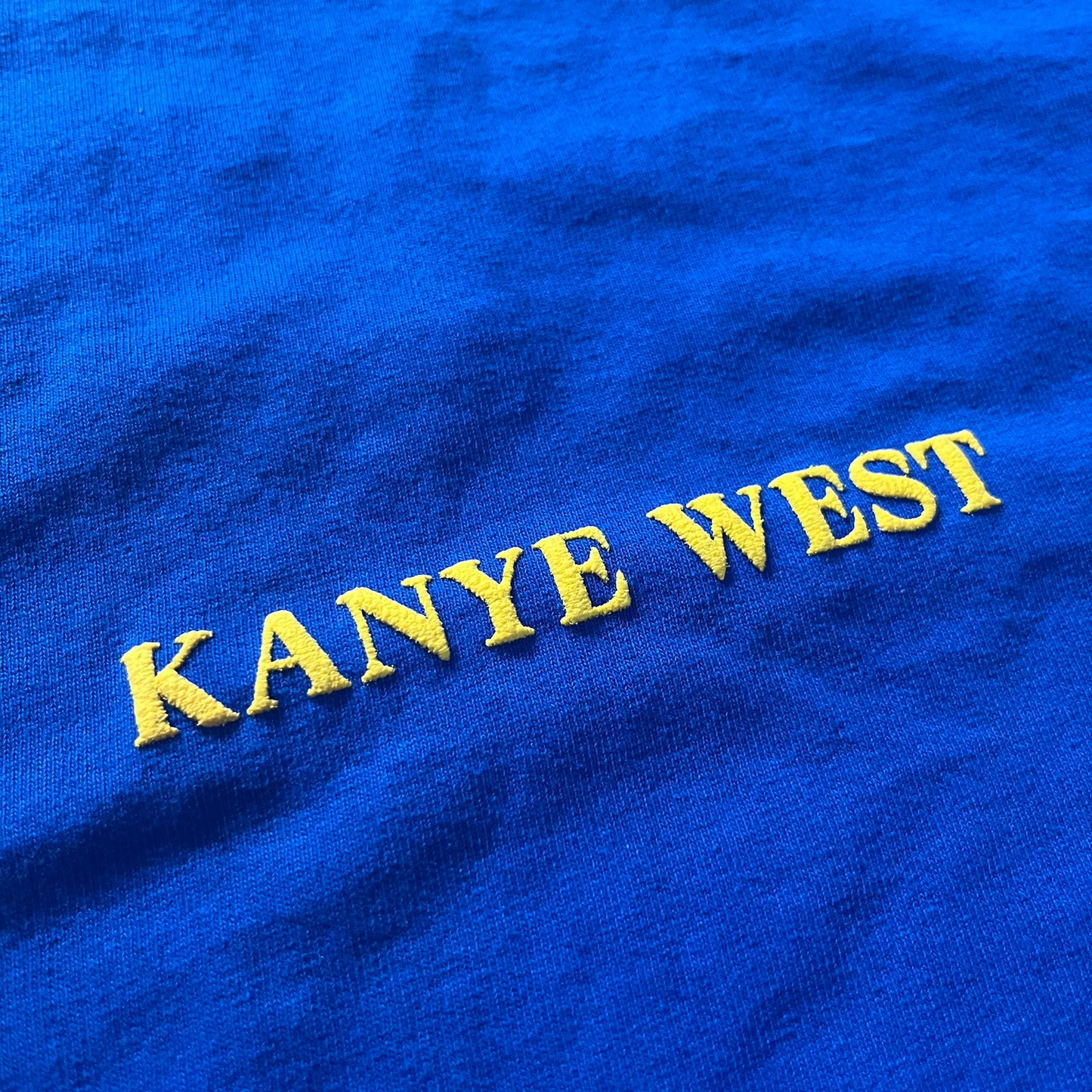 Blue fabric with 'Kanye West' embroidered in yellow