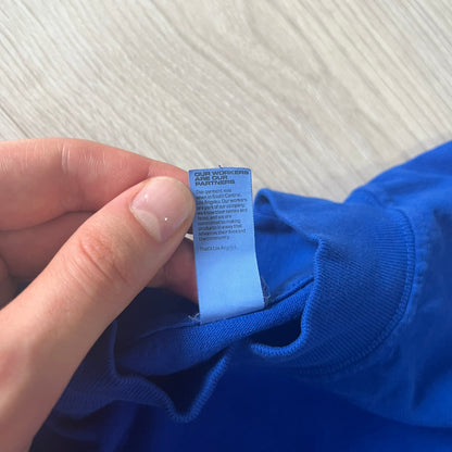 Hand holding a blue tag on a blue garment against a white background