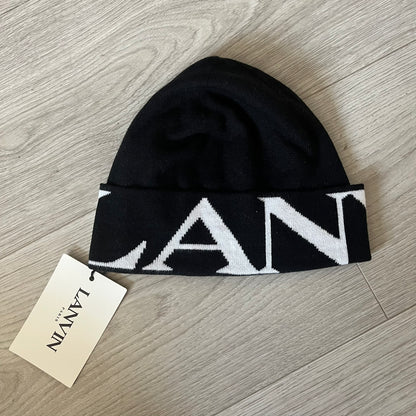 Black beanie with white logo on a wooden surface