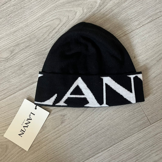 Black beanie with white logo on a wooden surface