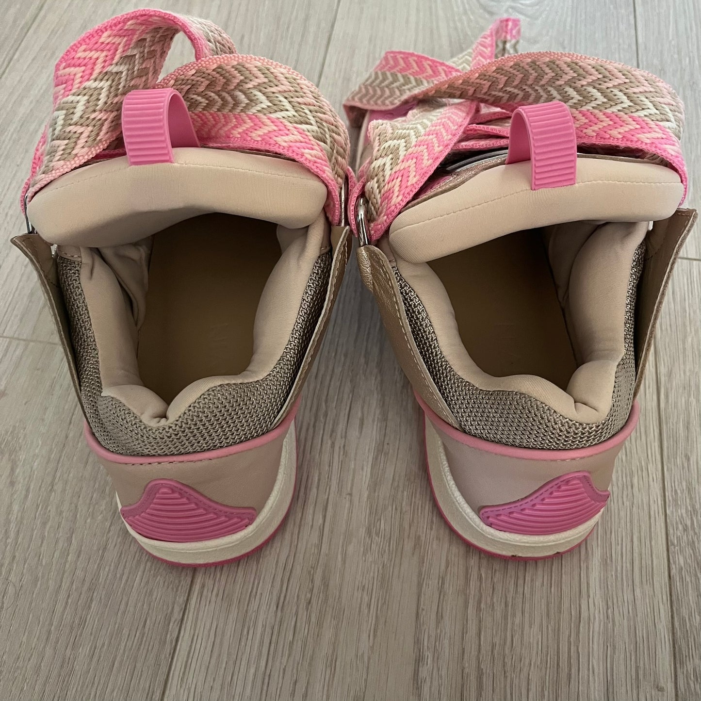 Pair of pink and beige sandals on a wooden floor