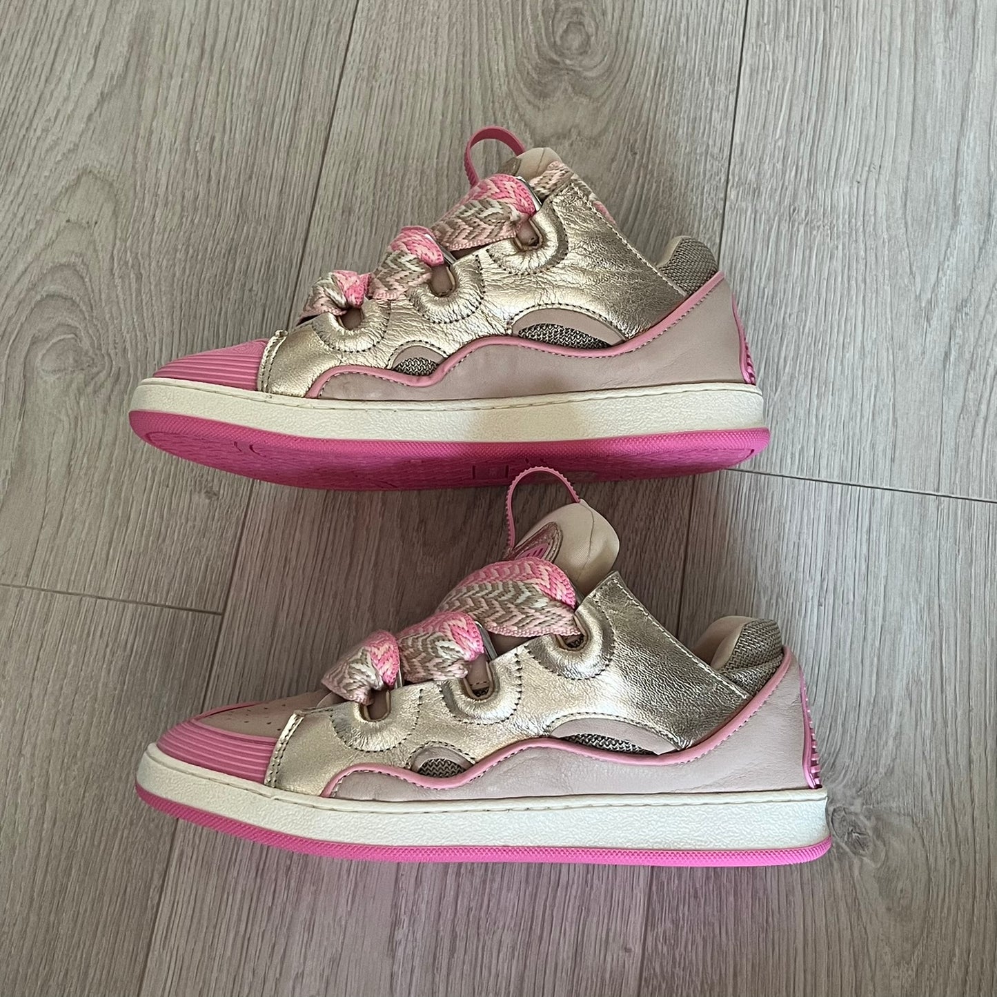 Pair of pink and gold sneakers on a wooden floor