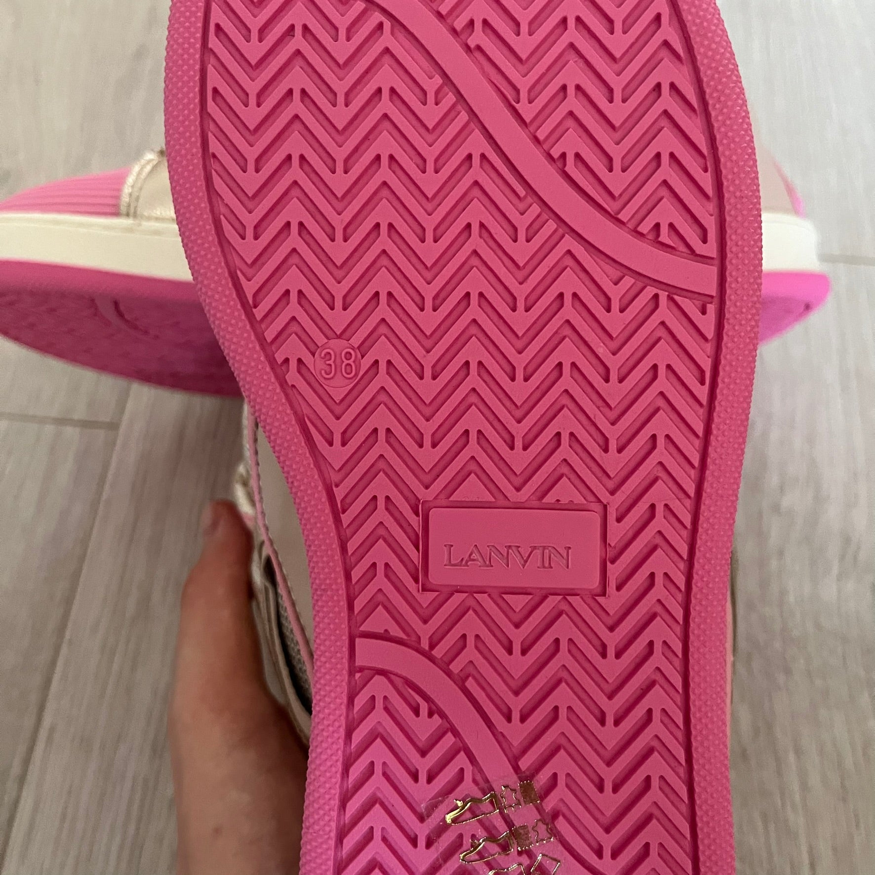 Close-up of a pink shoe sole with 'LANVIN' branding on a wooden floor.