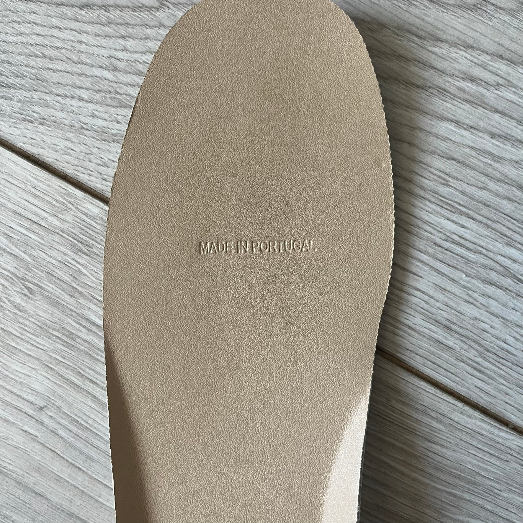 Beige shoe insole with 'Made in Portugal' text on a wooden surface