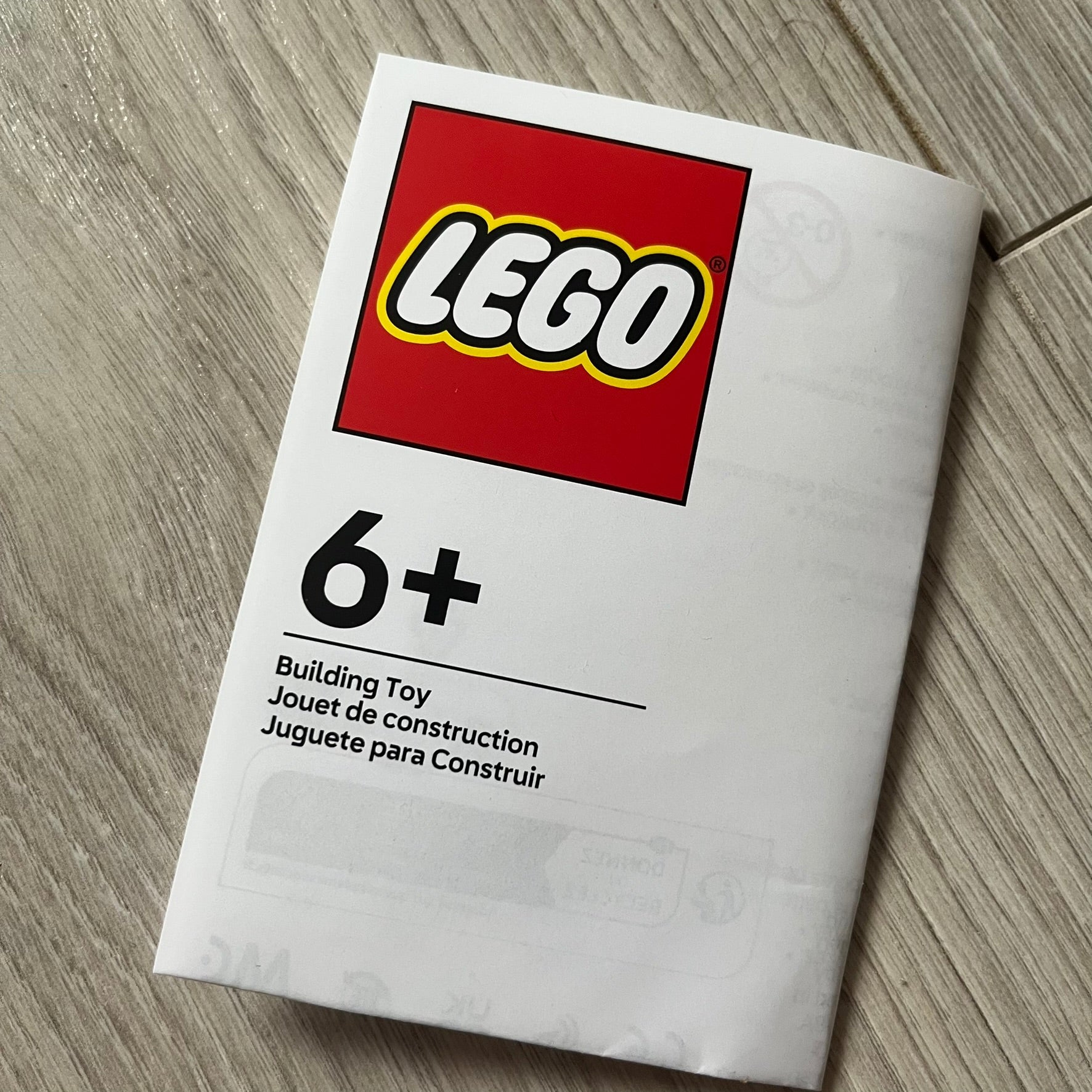 LEGO building toy packaging with age recommendation on a wooden surface