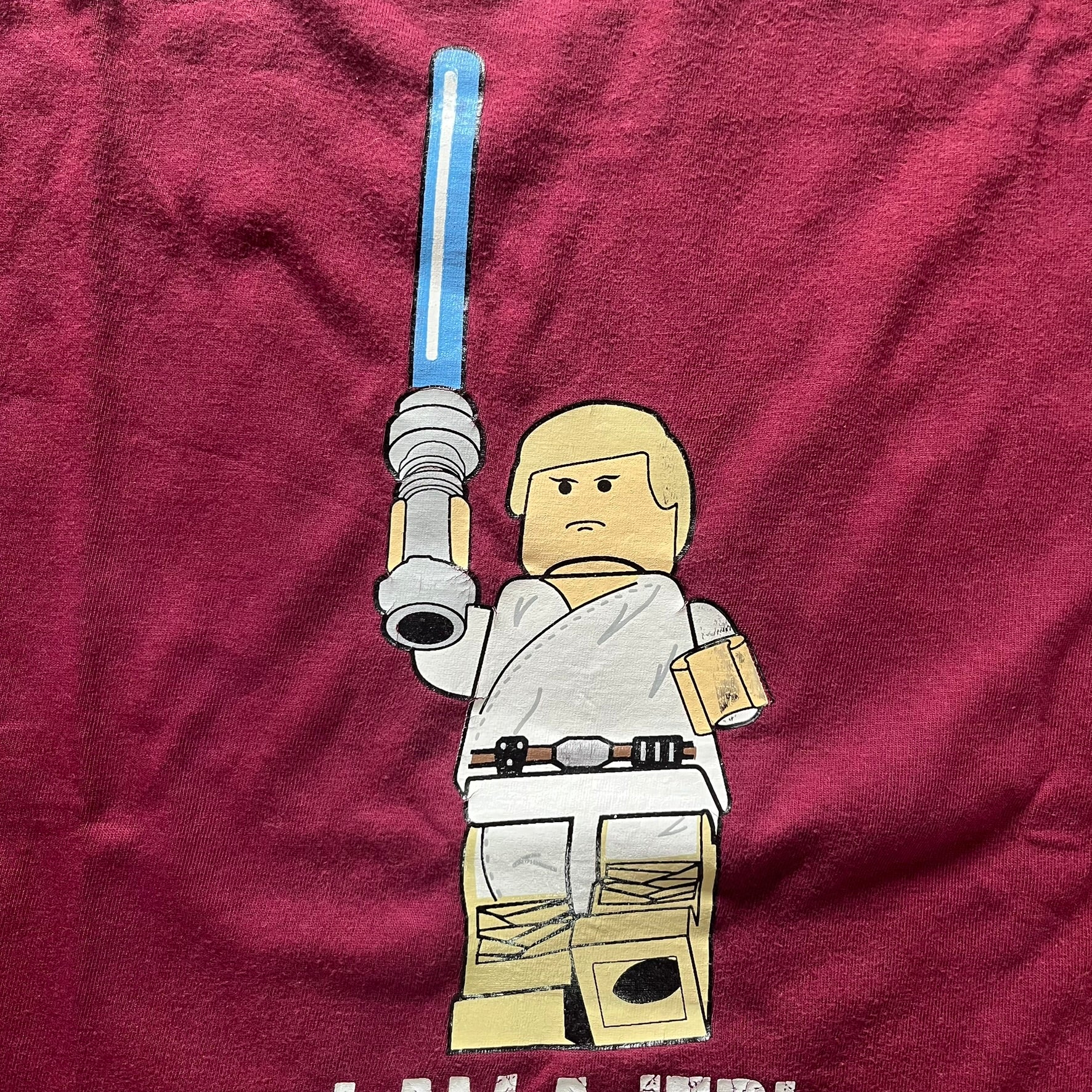 Lego figure of a character holding a lightsaber on a maroon background