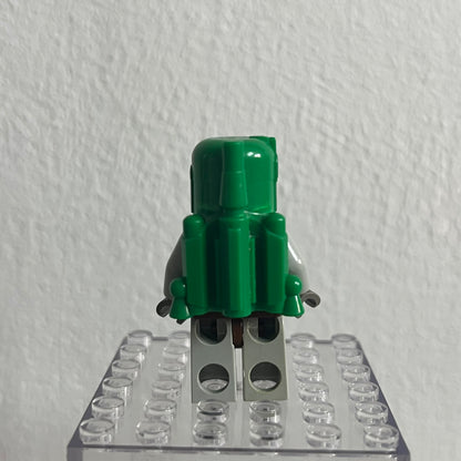Green toy figure on a clear baseplate against a white background