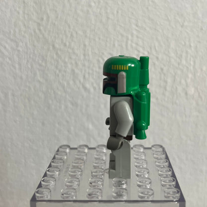 Green and gray robot figure on a clear base against a white wall