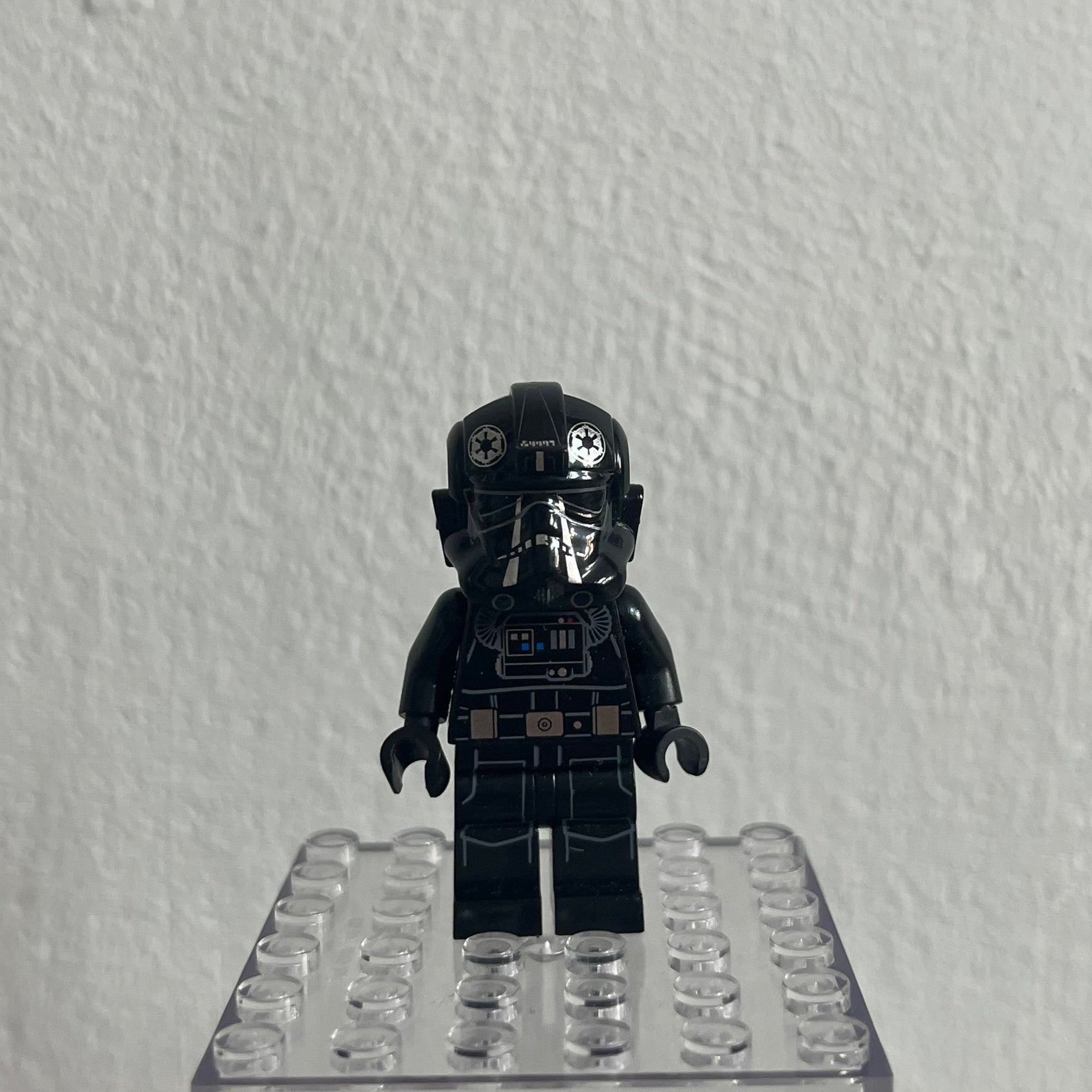 Black LEGO minifigure on a clear baseplate against a white background