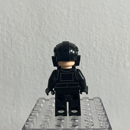 Black LEGO minifigure with helmet on a clear baseplate against a gray background