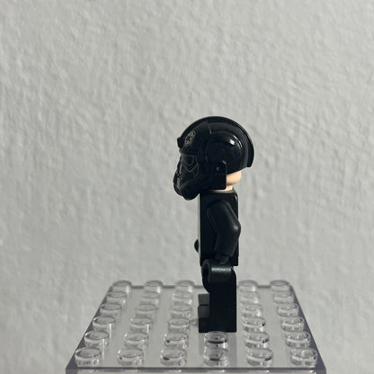 Black LEGO figure on a clear baseplate against a gray background