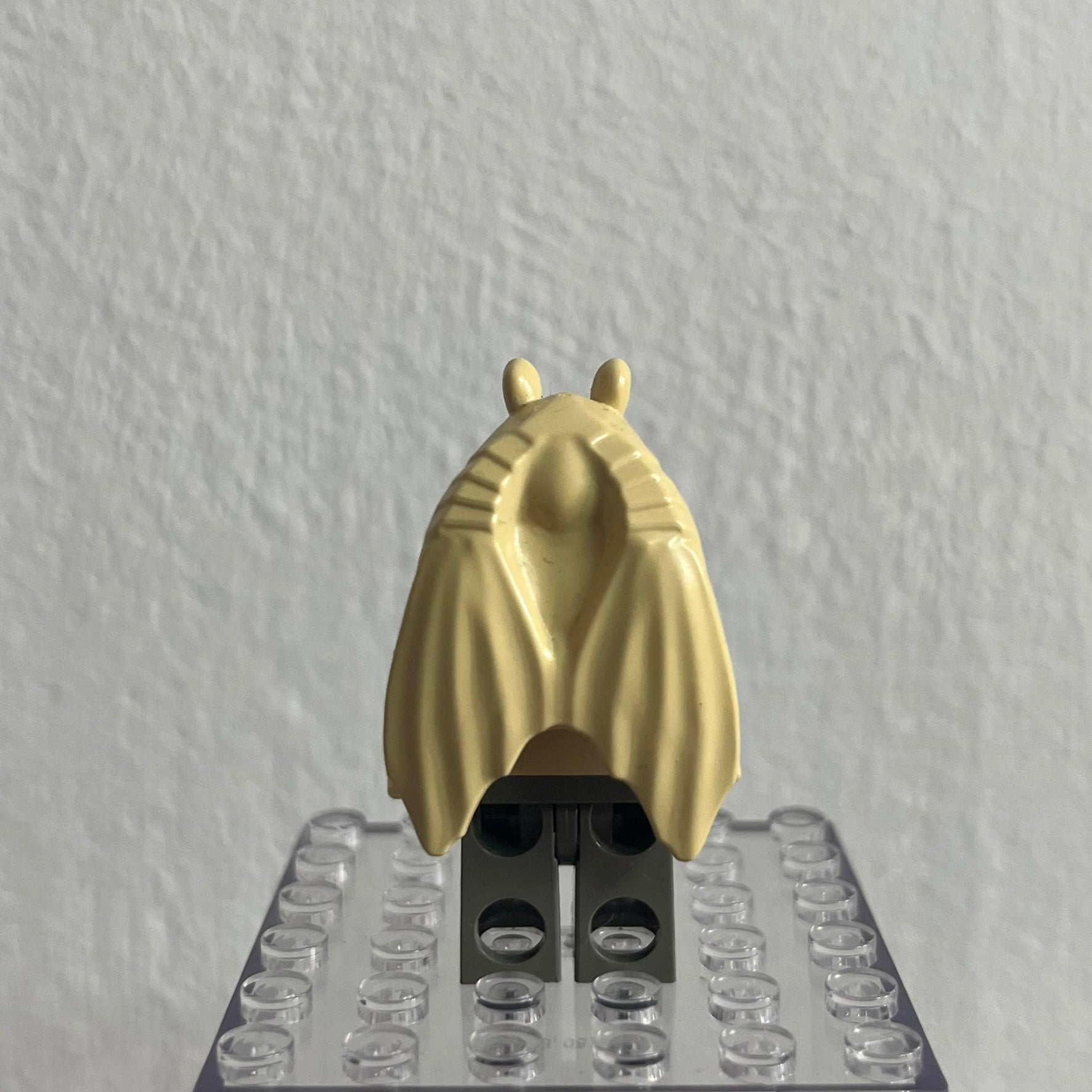 Gold-colored insect figure on a clear baseplate against a gray background
