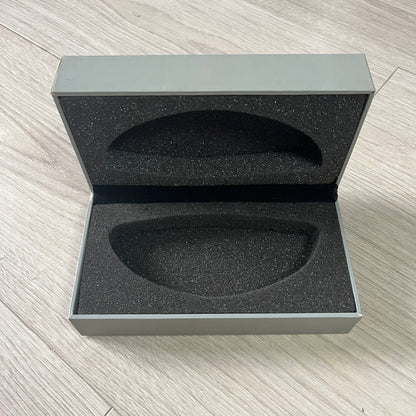 Open gray box with black interior foam on a light wooden surface