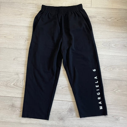 Black pants with 'MARGIELA 6' branding on a wooden floor