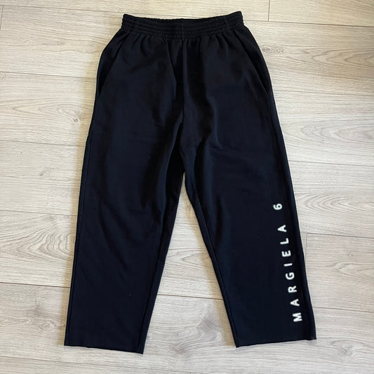 Black pants with 'MARGIELA 6' branding on a wooden floor
