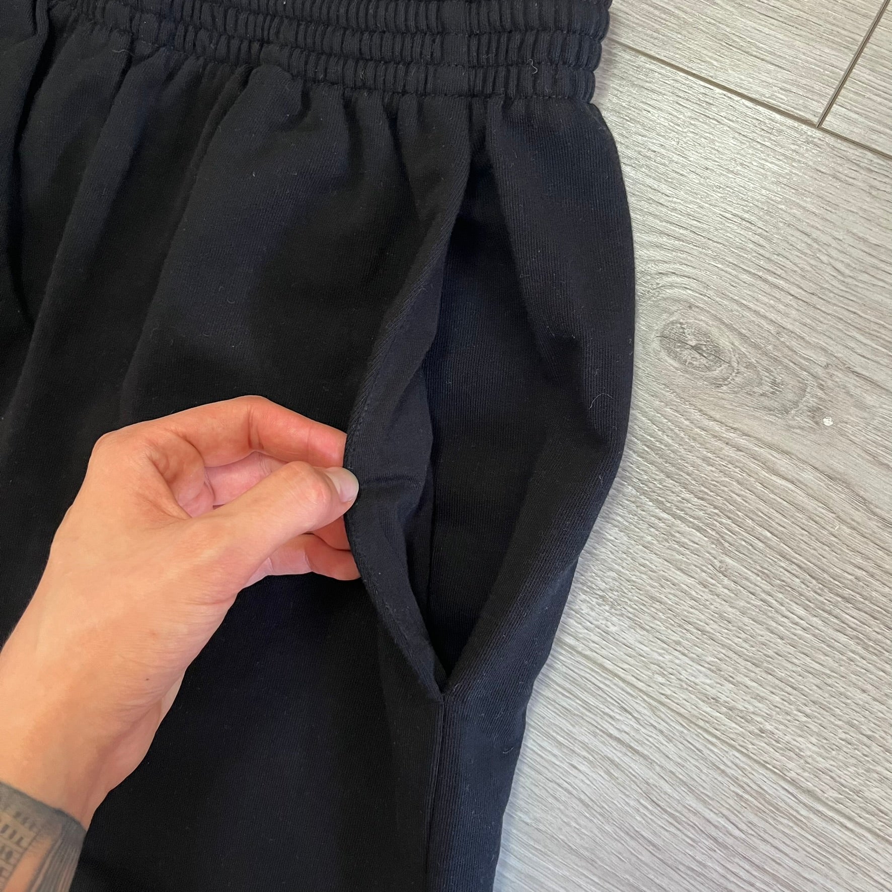 Person adjusting a black skirt on a wooden floor