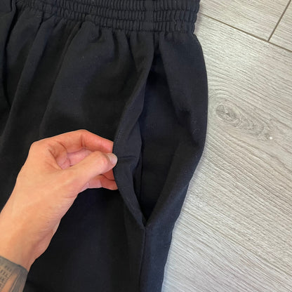 Person adjusting a black skirt on a wooden floor