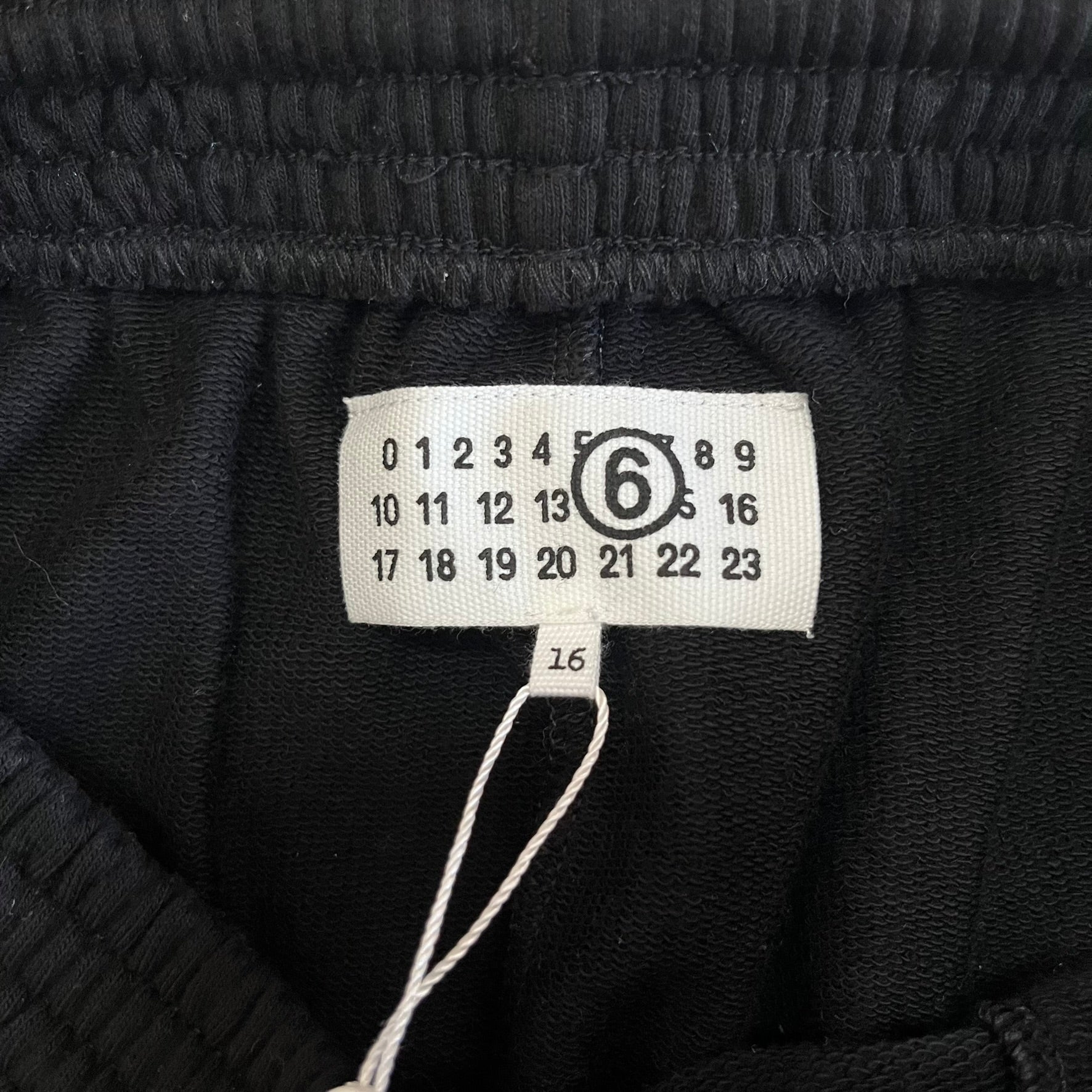 Close-up of a black textured fabric with a size label on a white background