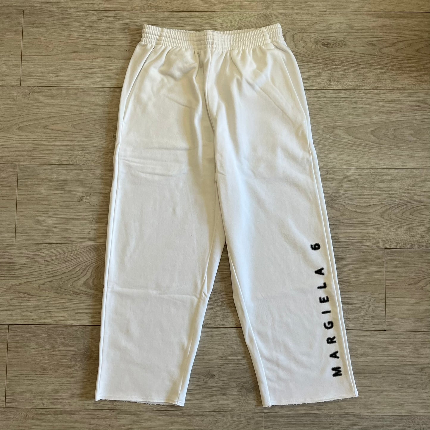 White pants with 'MARGIELA 6' text on a wooden floor