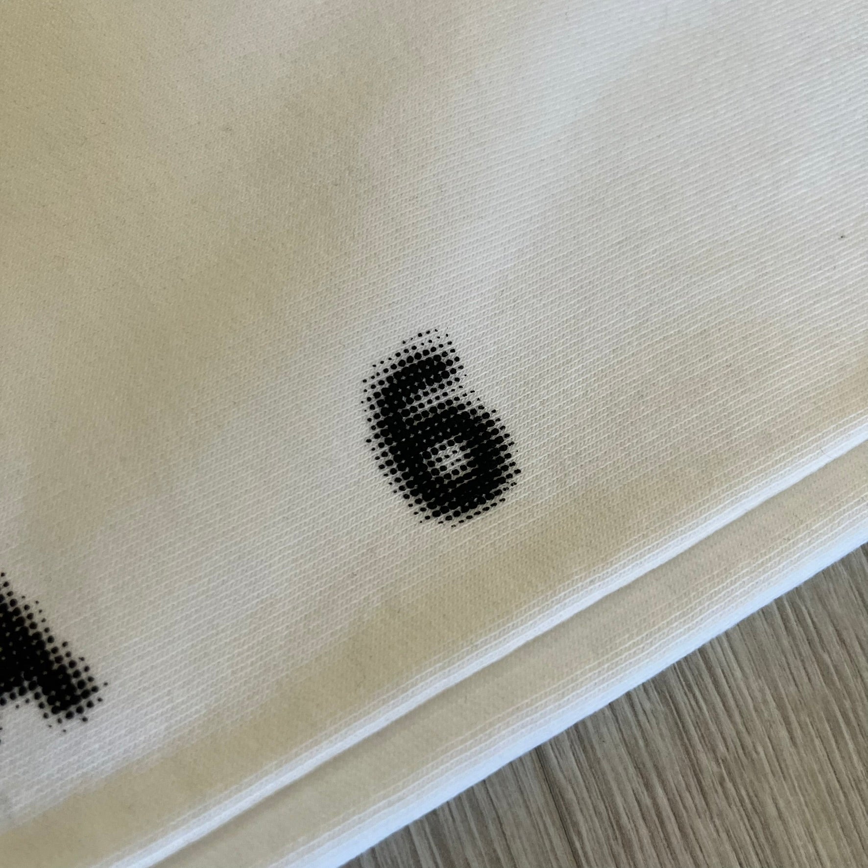 Close-up of a beige fabric with black printed numbers on a wooden surface