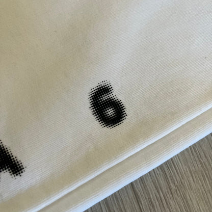 Close-up of a beige fabric with black printed numbers on a wooden surface