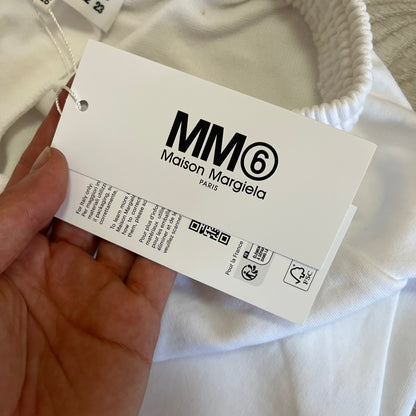 Maison Margiela label held by a hand with a white garment in the background