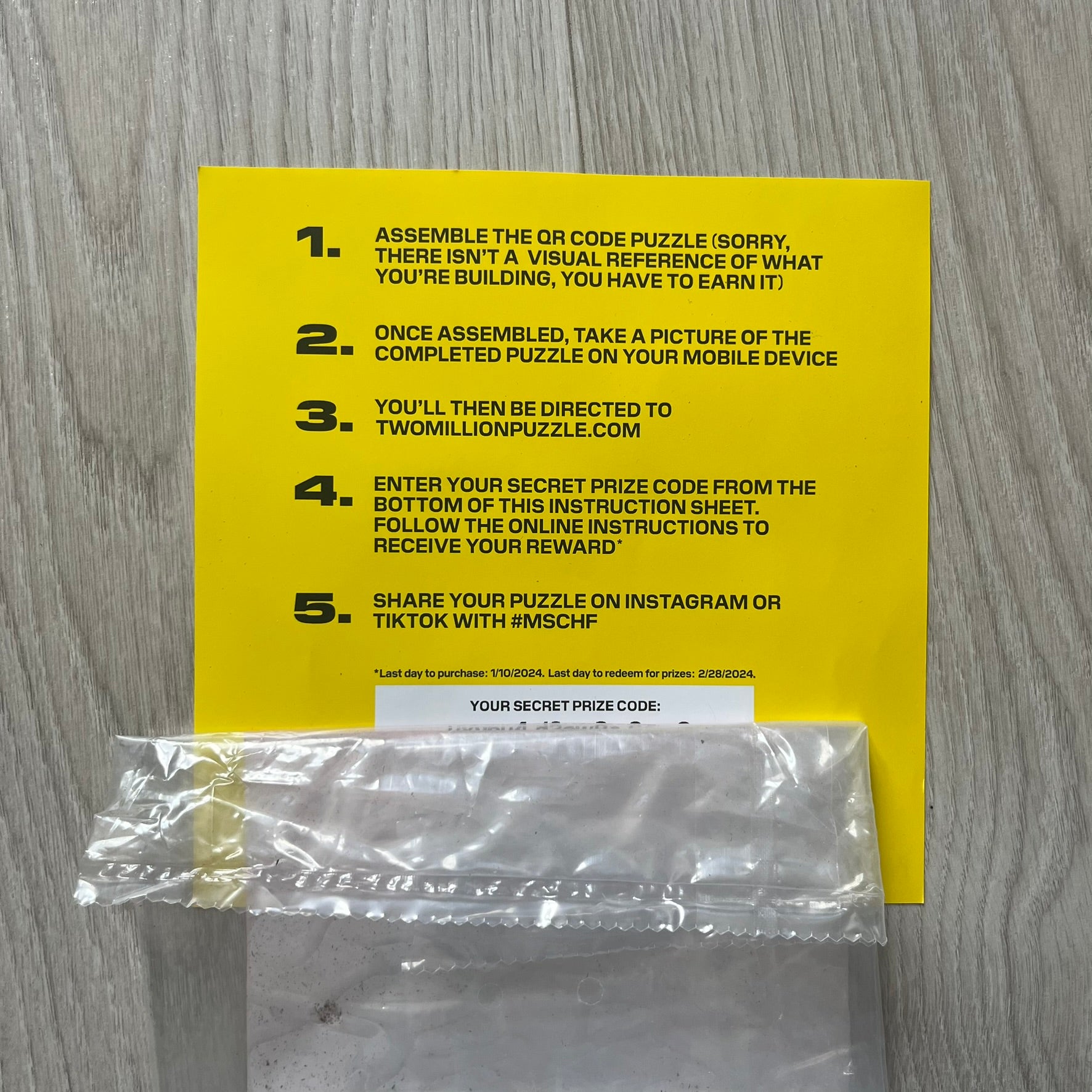 Yellow instruction sheet with text and a clear plastic bag on a wooden surface