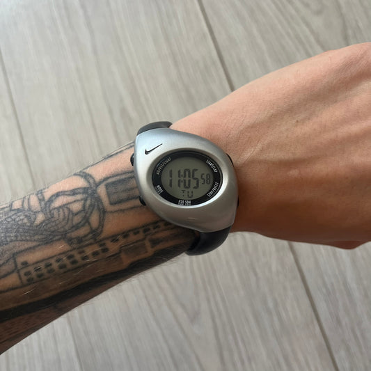 Digital watch on a wrist with tattoos, on a wooden surface