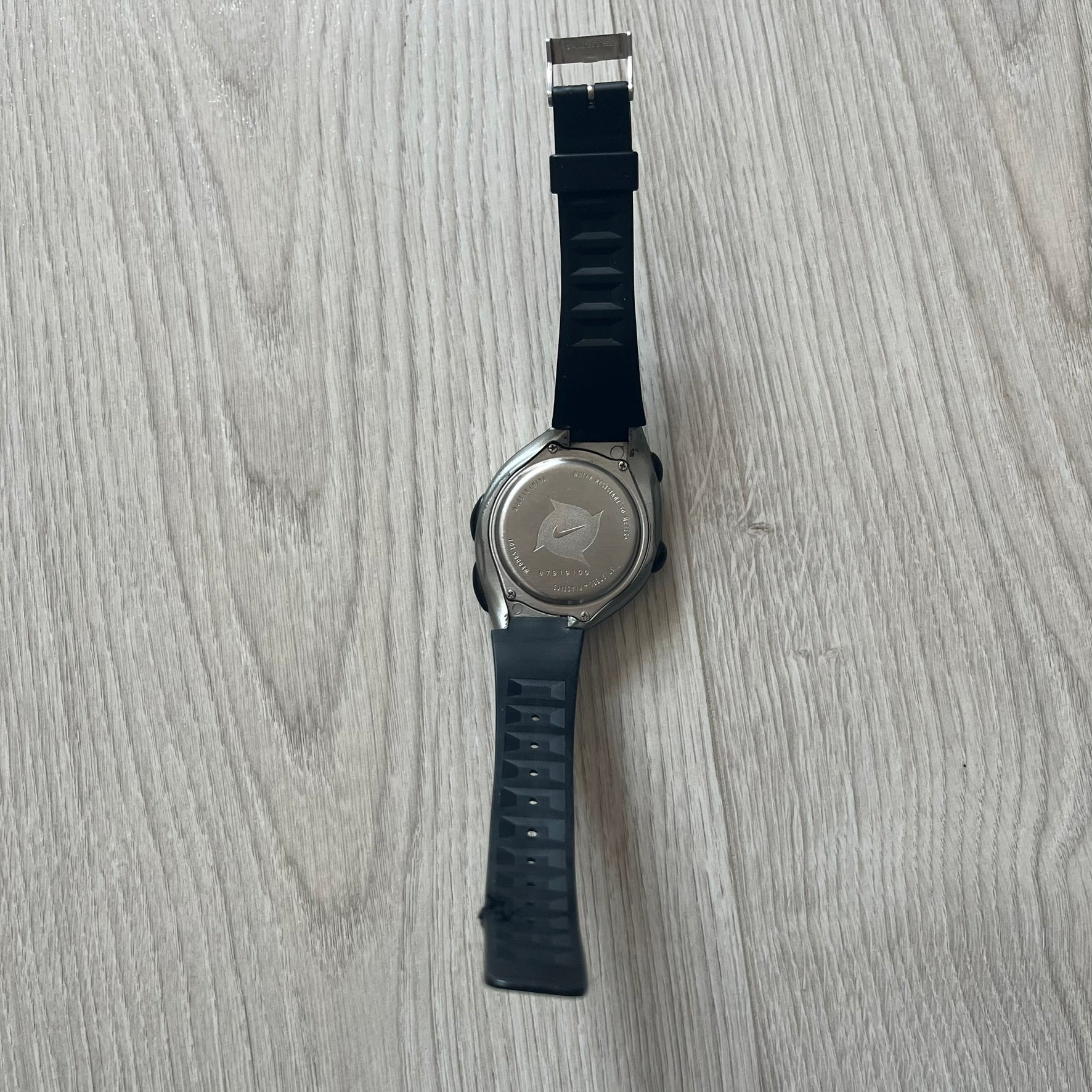 Wristwatch with black strap on a light wooden surface
