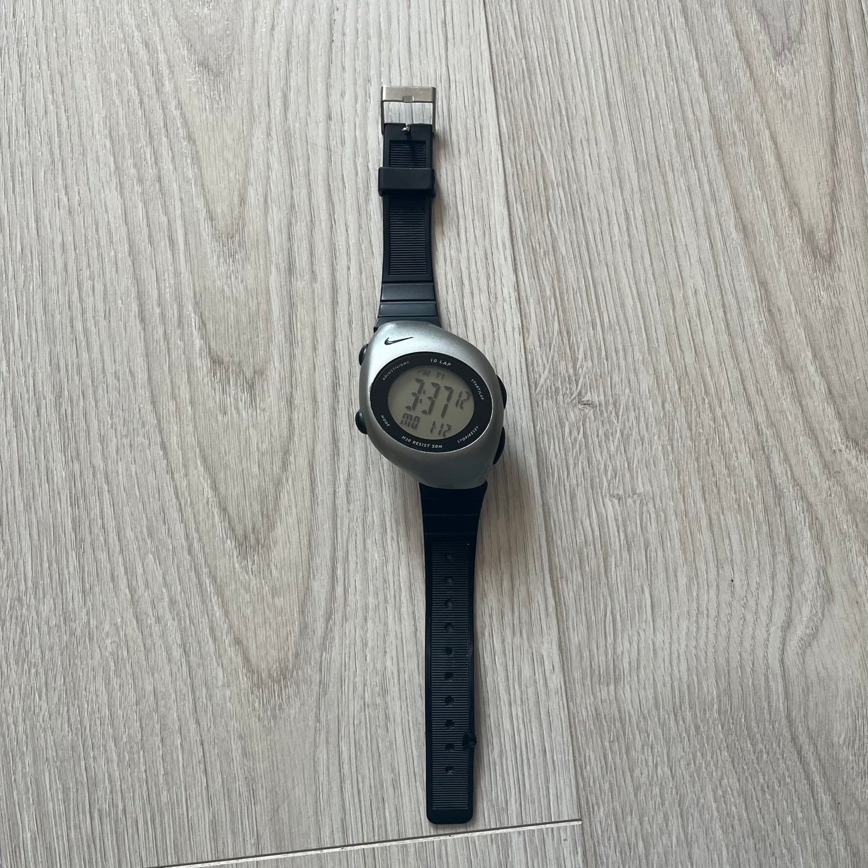 Digital watch with black strap on a light wooden surface