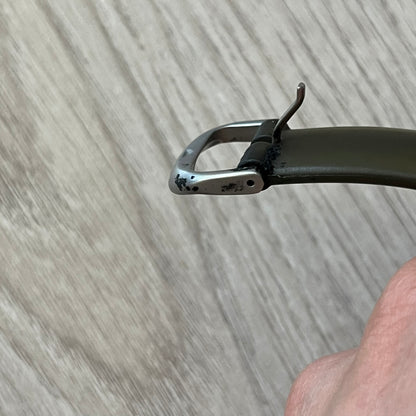 Close-up of a metal watch strap end on a wooden surface