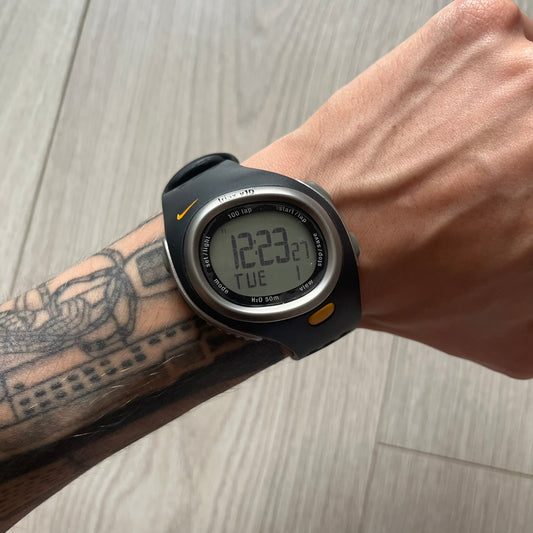 Digital watch on a wrist with tattoos, on a wooden surface