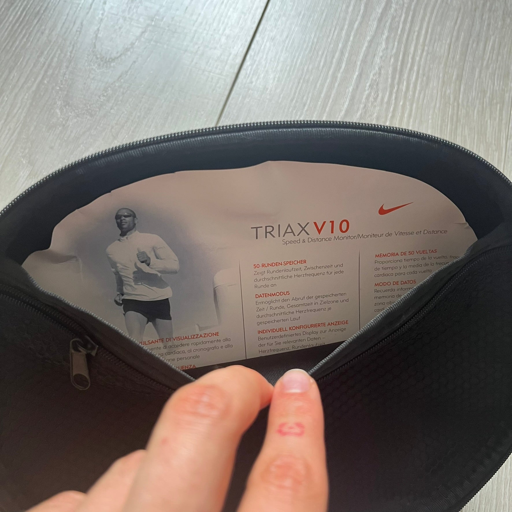 Person opening a black bag with 'TRIAX V10' and Nike branding visible.