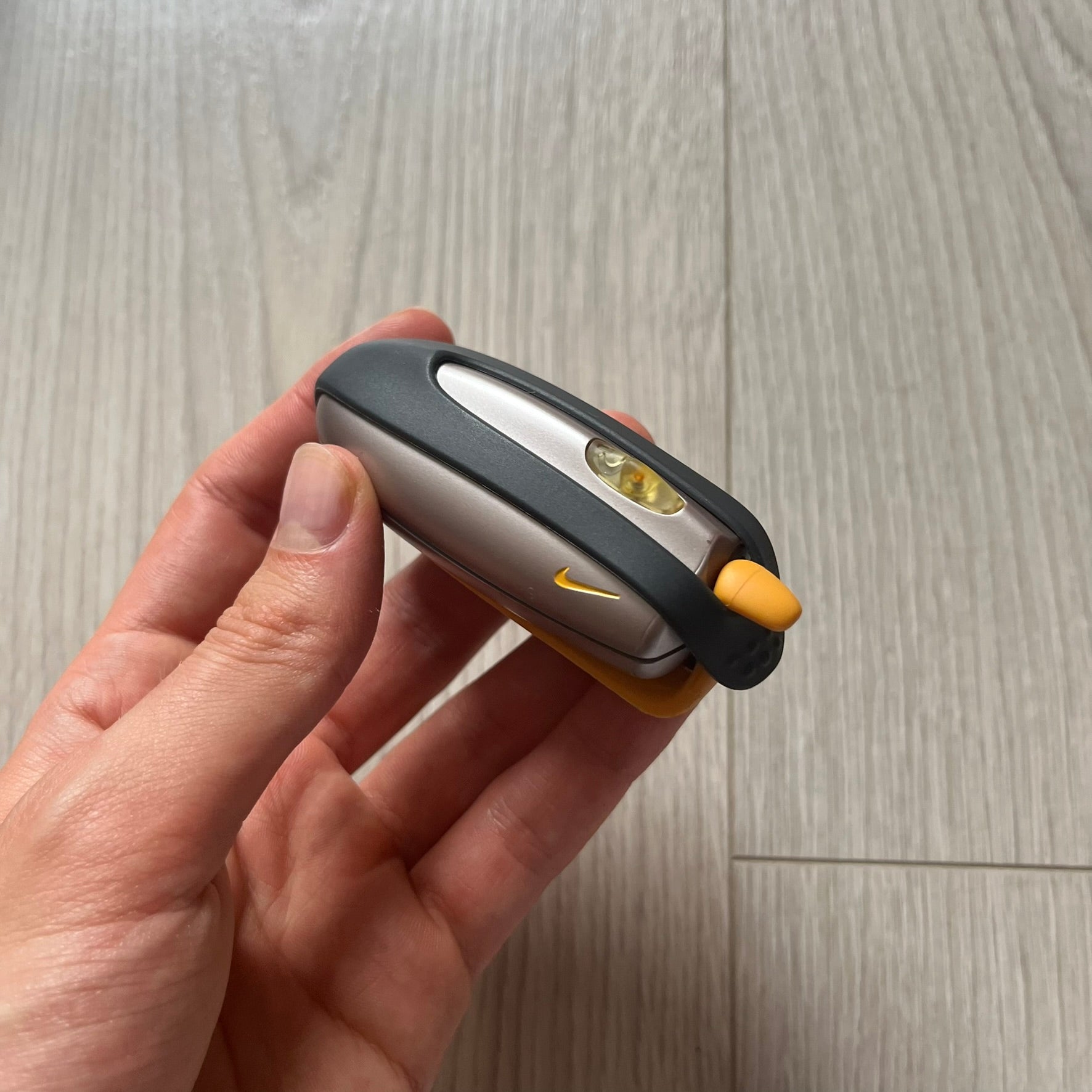 Hand holding a small flashlight with a visible brand logo on a wooden surface