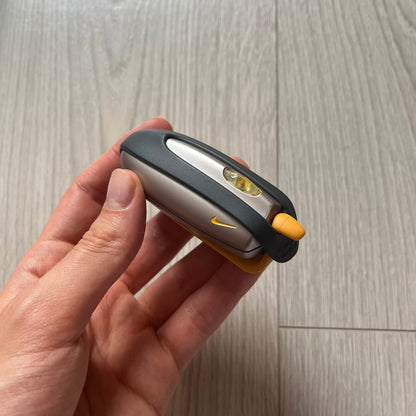 Hand holding a small flashlight with a visible brand logo on a wooden surface