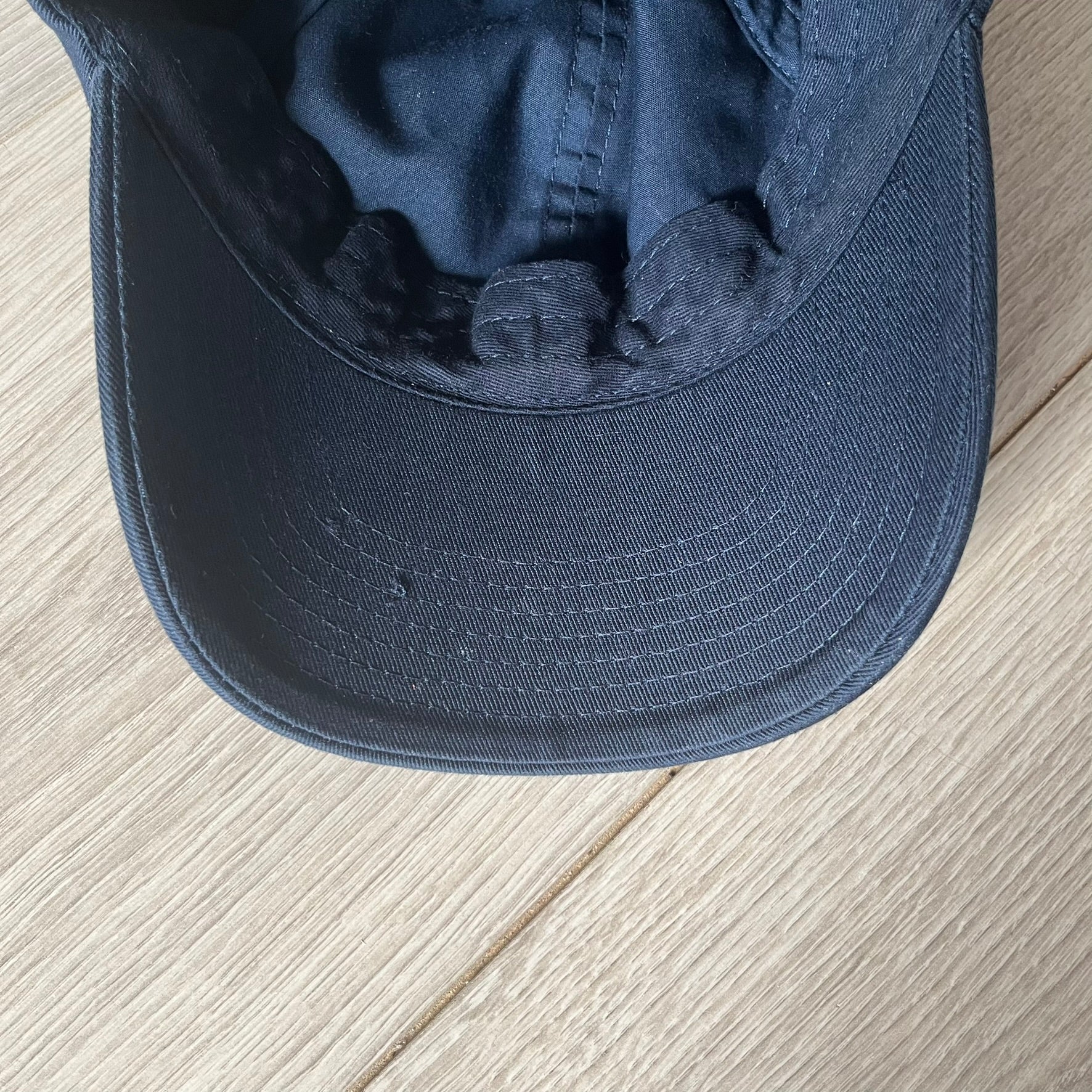 Navy blue cap on a light wooden surface
