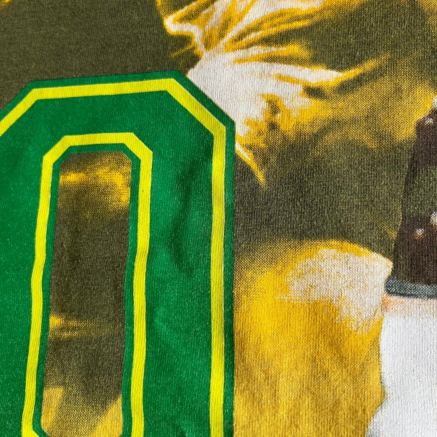 Close-up of a green letter 'O' with a yellow outline on a fabric background.