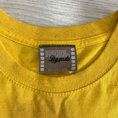 Close-up of a yellow shirt with a 'Reel Legends' label on a gray background