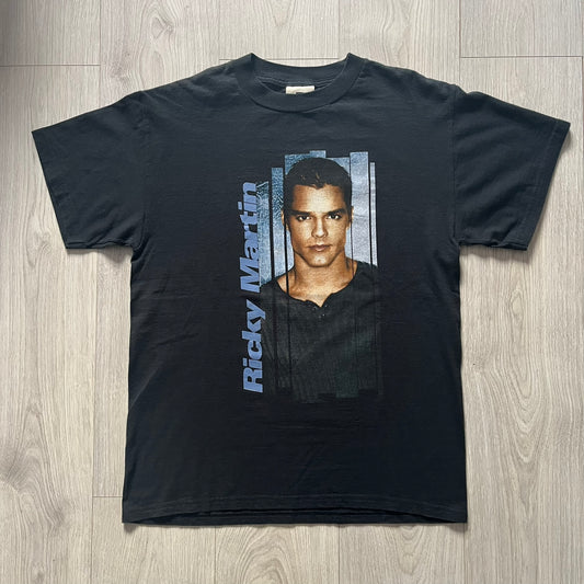 Black t-shirt with a graphic of a person and 'Ricky Martin' text on a wooden surface