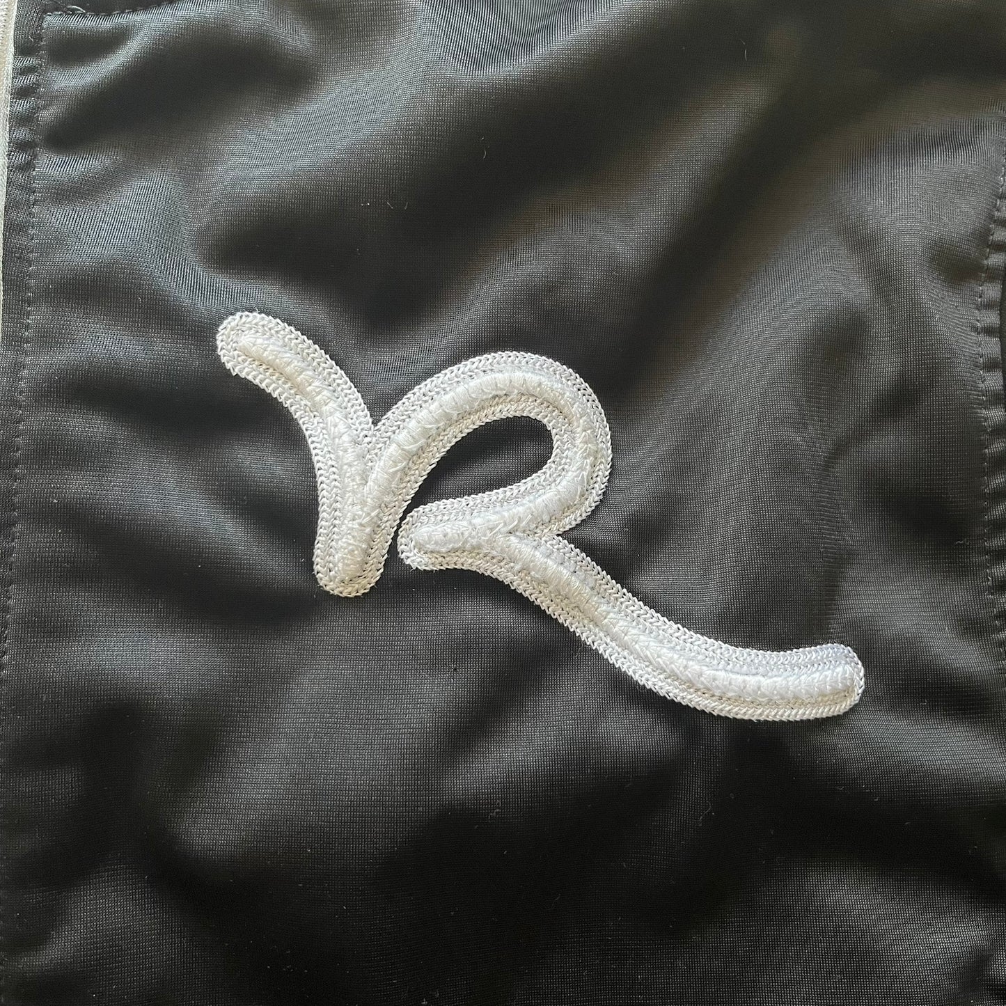 White embroidered logo on a black fabric background