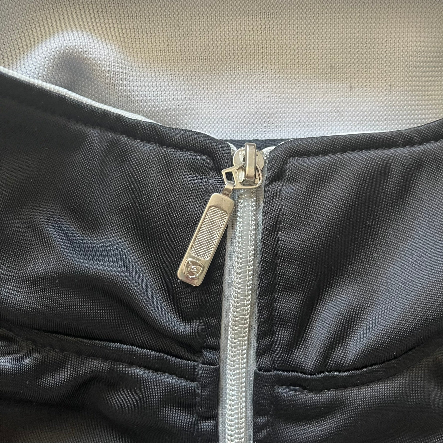 Close-up of a black jacket with a silver zipper and visible brand logo.