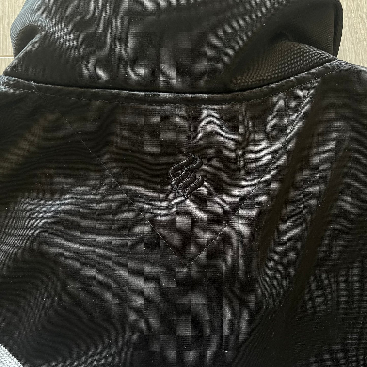 Close-up of a black jacket with a logo on the chest pocket.