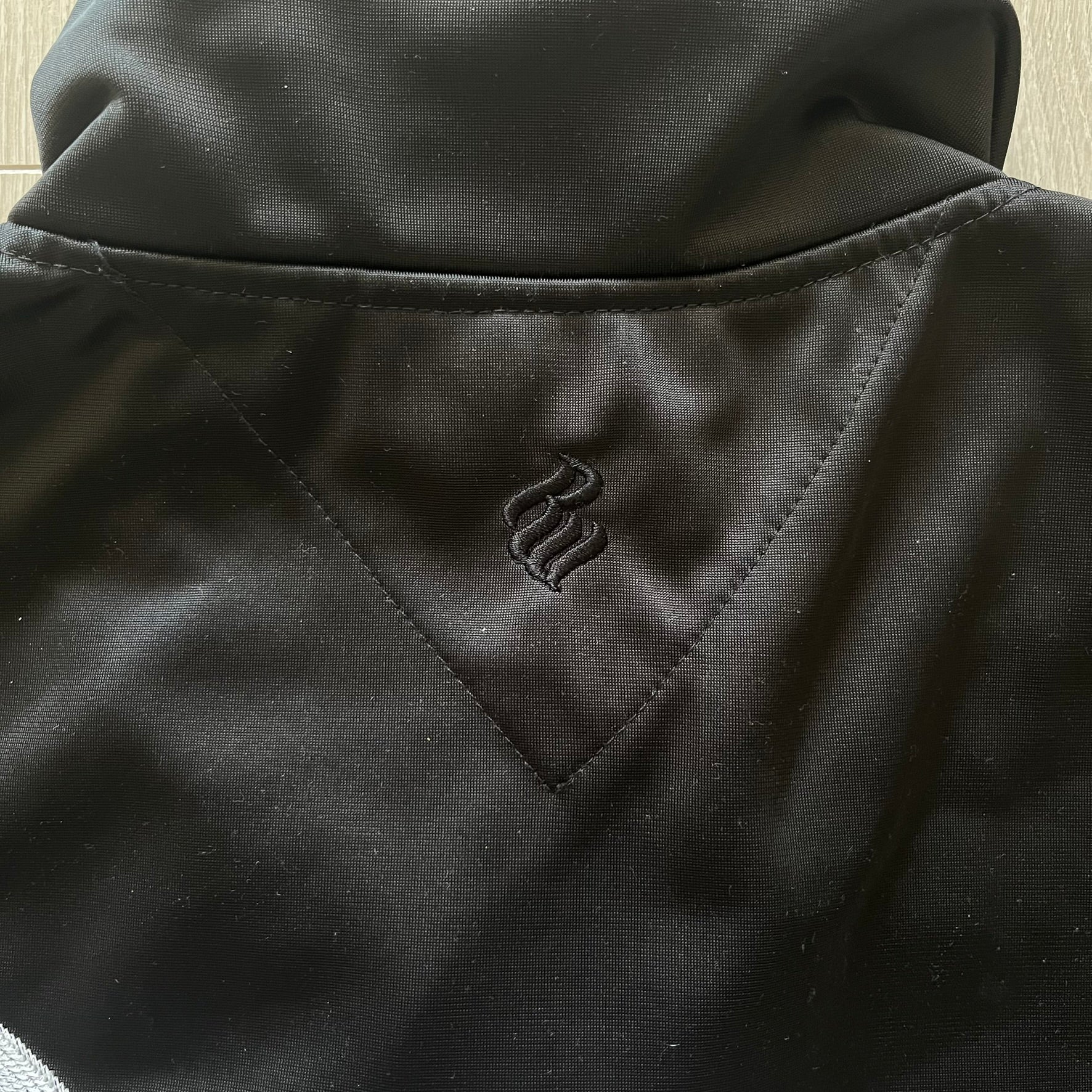 Close-up of a black jacket with a logo on the chest pocket.