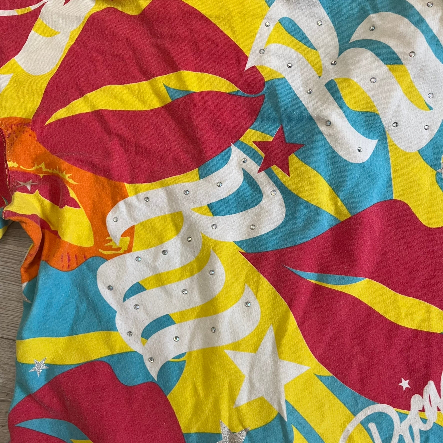 Colorful tie-dye shirt with star and moon patterns on a wooden surface
