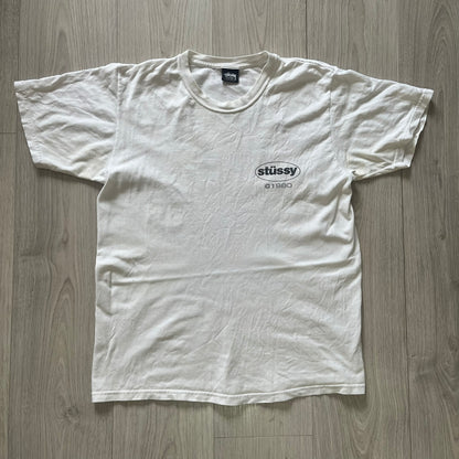 White t-shirt with Stussy logo on a wooden surface